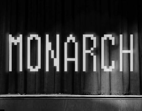 The glowing MONARCH title card on a stage curtain